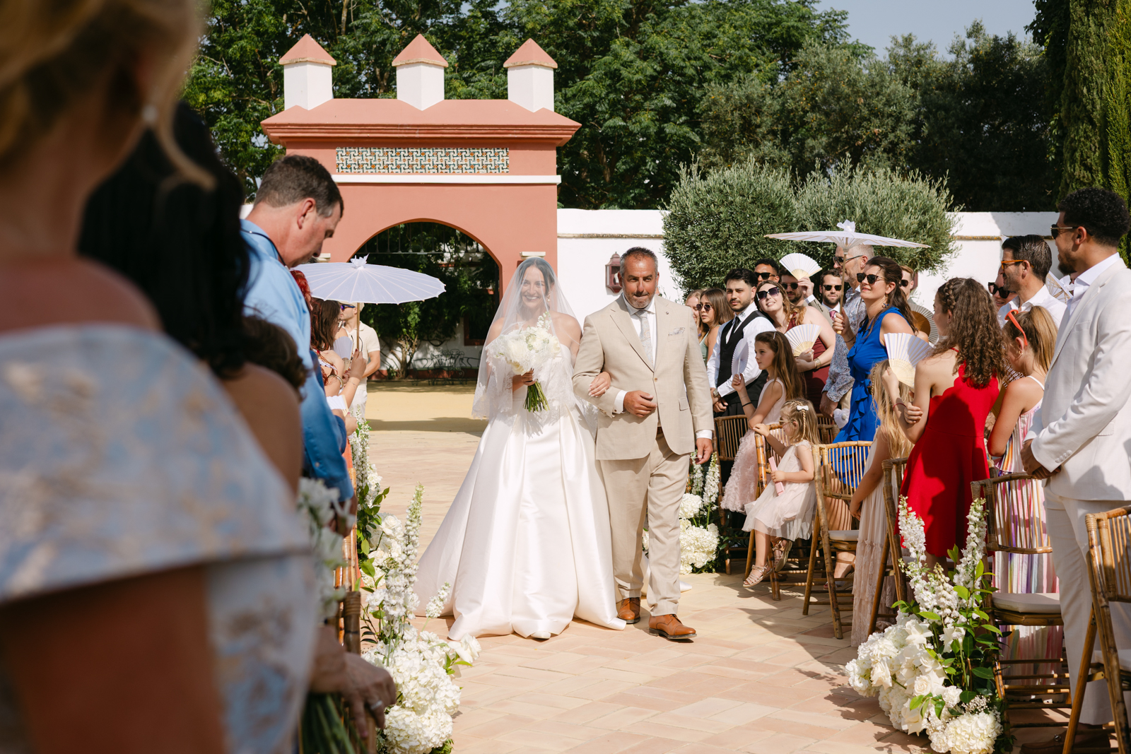 BlancoWhite_WeddingDestination_HaciendadeOran 0084 Entrada de la novia velada con su padre acompañandola al altar