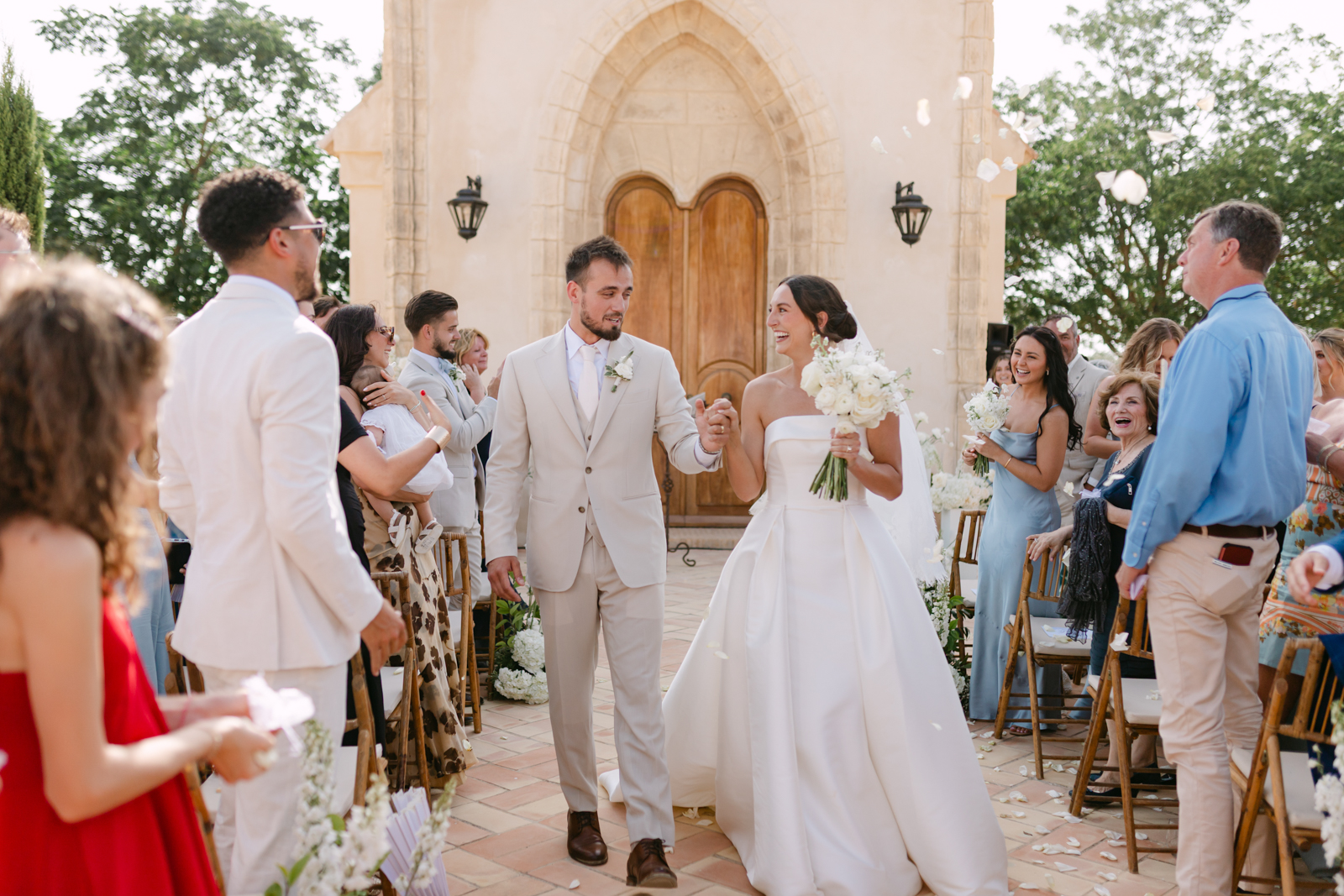BlancoWhite_WeddingDestination_HaciendadeOran 0107 Salida de los novios divertida y natural mientras los invitados aplauden en Hacienda de Oran Sevilla